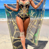 Aitana - maillot une pièce noir à motifs dorés et verts avec paréo assorti sur la plage