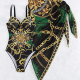 Aitana - maillot une pièce noir à motifs dorés et verts avec paréo assorti présenté à plat